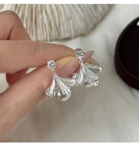 Detail of silver ginkgo leaf earrings featuring sparkling zircons and round pearls
