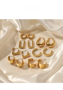 Flat lay of diverse geometric 14K gold-plated stainless steel earrings on white silk fabric