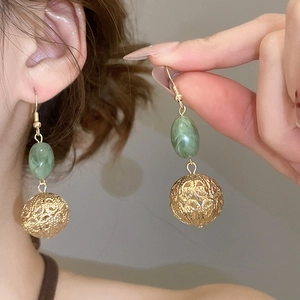 Gros plan détaillé de boucles d'oreilles boules dorées avec perles résine marbrée