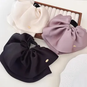Detailed view of elegant satin bow hair claws in cream, pink, and black colors