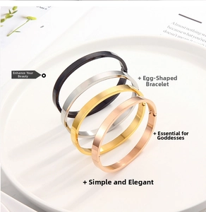 Minimalist oval bangles in black, gold, silver and rose gold shown on a ceramic plate