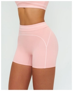 Detail of pink high-waisted gym shorts with white contrast stitching and curved seams