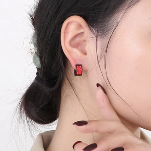 Black C-shaped stainless steel earrings with red crystal inlay on female model