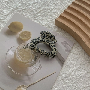 Detail of minimalist cream acetate claw clip with black speckled pattern on a tray