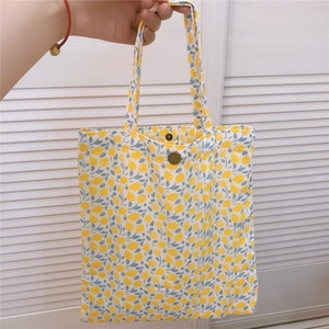 Détail d'un cabas en toile à fleurs avec imprimé citron et bouton-pression en bronze