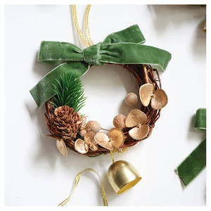 Close-up of a rustic Christmas wreath with green velvet bow, pine cone, and gold bell detail