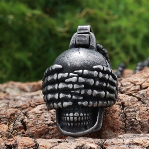 Detail of gothic stainless steel skull pendant with bone hands covering eyes on tree bark