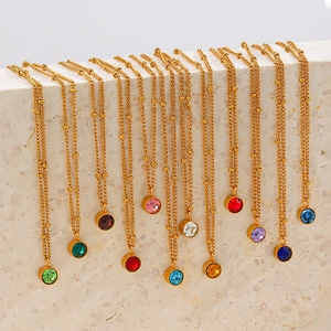 18K gold plated stainless steel birthstone necklaces draped on textured stones