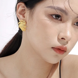 Detailed close-up of 18K gold-plated woven fan-shaped earrings on a model's ear
