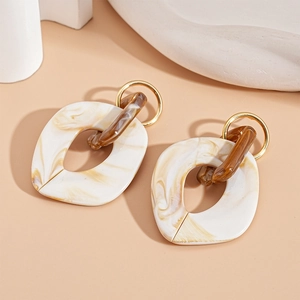 Macro shot of geometric acrylic resin earrings with marble pattern and gold metal ring