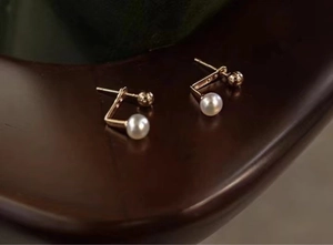 Detailed view of freshwater pearl stud earrings with polished gold metal finish