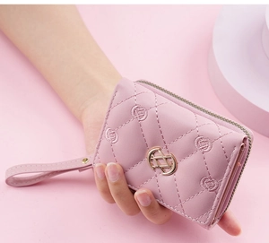 Pink quilted wallet detail with gold interlocking logo and matching wrist strap