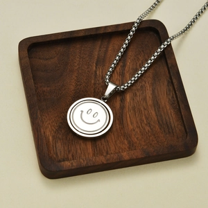 Macro view of rotating smiley face pendant on a steel ball chain over wood