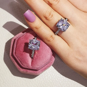 Detail of silver rings with cushion-cut purple gemstones in a pink velvet jewelry box