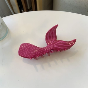 Détail d'une pince à cheveux queue de sirène rose avec texture d'écailles brillante