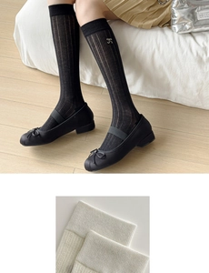 Detail view of knit slouch socks with delicate bow embroidery and textured patterns