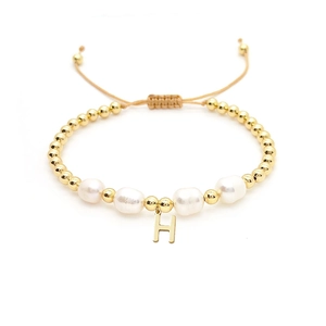 Detail of baroque pearl bracelet with gold beads and letter H pendant on woven cord