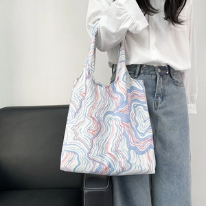 Detail of floral canvas tote bag with blue and red marble pattern on a shoulder