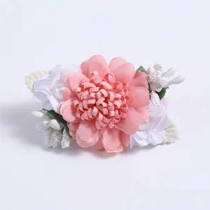 Detail of handmade fabric flower clip with pink petals, white pearls and green leaves