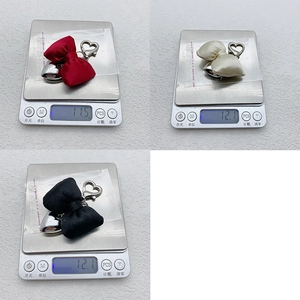Detail showing various colors of satin bow keychains on a scale for weight display