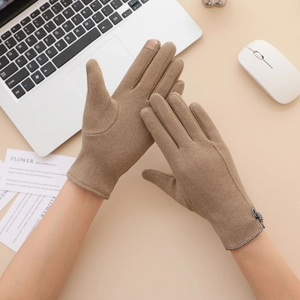 Brown suede touch screen gloves for women with delicate bow detail on a desk