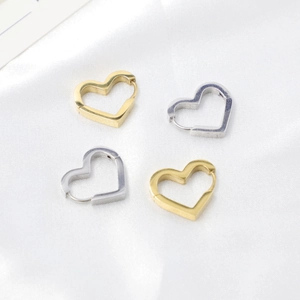 Boucles d'oreilles cœur creux dorées et argentées sur soie blanche avec éclat métallique