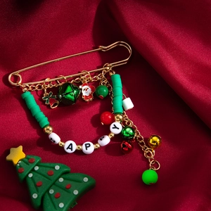Détail de la broche épingle de Noël avec perles HAPPY et breloques sur soie rouge