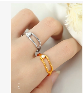 Detail of silver and gold safety pin rings with embedded pearls on a model's fingers