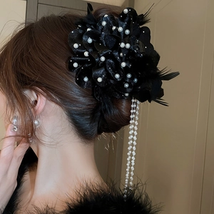 Detail of elegant black hair claw with pearls, feathers, and flowing sequin ribbon