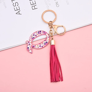 Detailed shot of letter Q keychain with floral pattern and magenta suede tassel