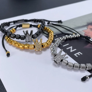 Detailed shot of crown charms on bead bracelets in black, gold, and silver finishes