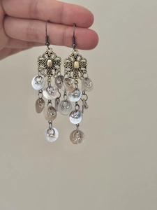 Detail of bronze floral hollow earrings with cascading white shell tassels