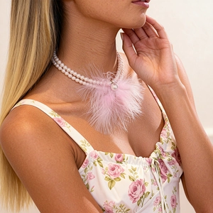 Detail of double-layer pearl necklace featuring a soft pink feather pendant on a model
