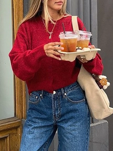 Detail view of a stylish red knitted cardigan paired with casual blue denim jeans