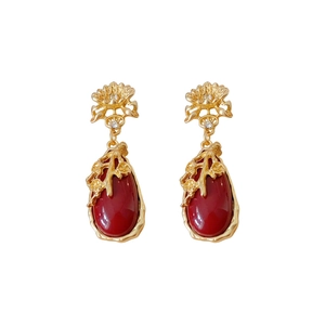Vintage gold earrings with flower stud and red teardrop gemstone on white background