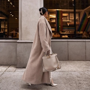 Manteau long en polaire teddy beige et sac à main en cuir gris dans la rue
