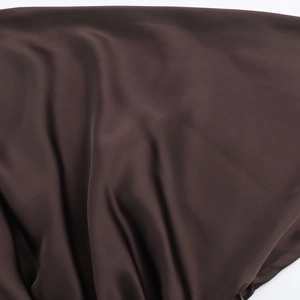 Primo piano del tessuto di raso marrone scuro con trama liscia ed elegante drappeggio