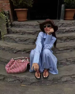 Detail of blue striped shirt and pants set with a brown straw hat and tote bag