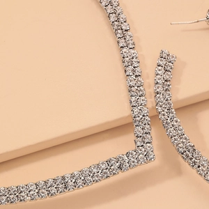 Détail macro de boucles d'oreilles géométriques argentées avec strass double rangée