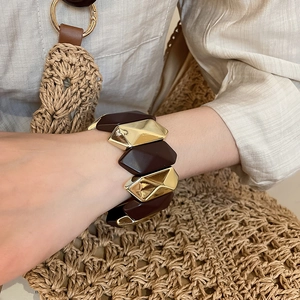 Close-up of wide geometric stretch bracelet with brown and gold moon segments on wrist