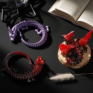 Artistic crystal dragon resin figurines in purple and red hues on mystical background