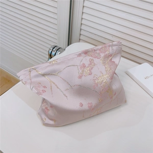 Détail d'un étui à mouchoirs en satin rose avec motif floral jacquard sur une coiffeuse