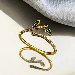 Vintage branch ring with green enamel leaves and antique gold finish in mirror reflection
