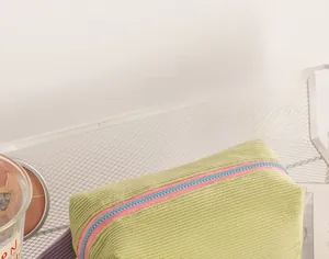 Dettaglio della trousse in velluto a coste verde con cerniere colorate a contrasto