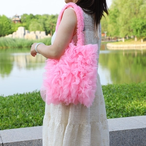 Close-up of pink ruffled tulle shoulder bag with layered lace details in park setting