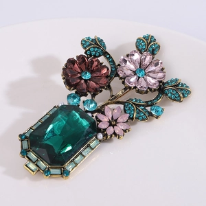Detailed macro of Baroque vase brooch with emerald gemstone and colorful floral crystals