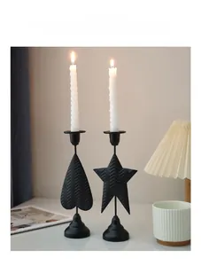 Detail of black heart and star metal candle holders with wave texture on a modern desk