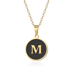Macro di una collana d'oro con ciondolo rotondo in smalto nero e lettera M dorata