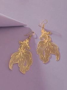 Detailed close-up of hollowed-out golden koi fish earrings on a purple background
