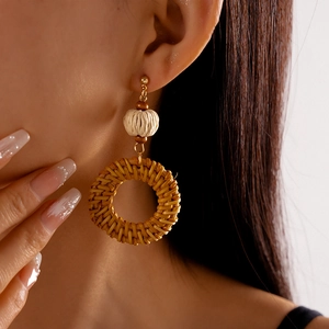 Close-up of bohemian rattan hoop earrings with textured cream beads worn by a model